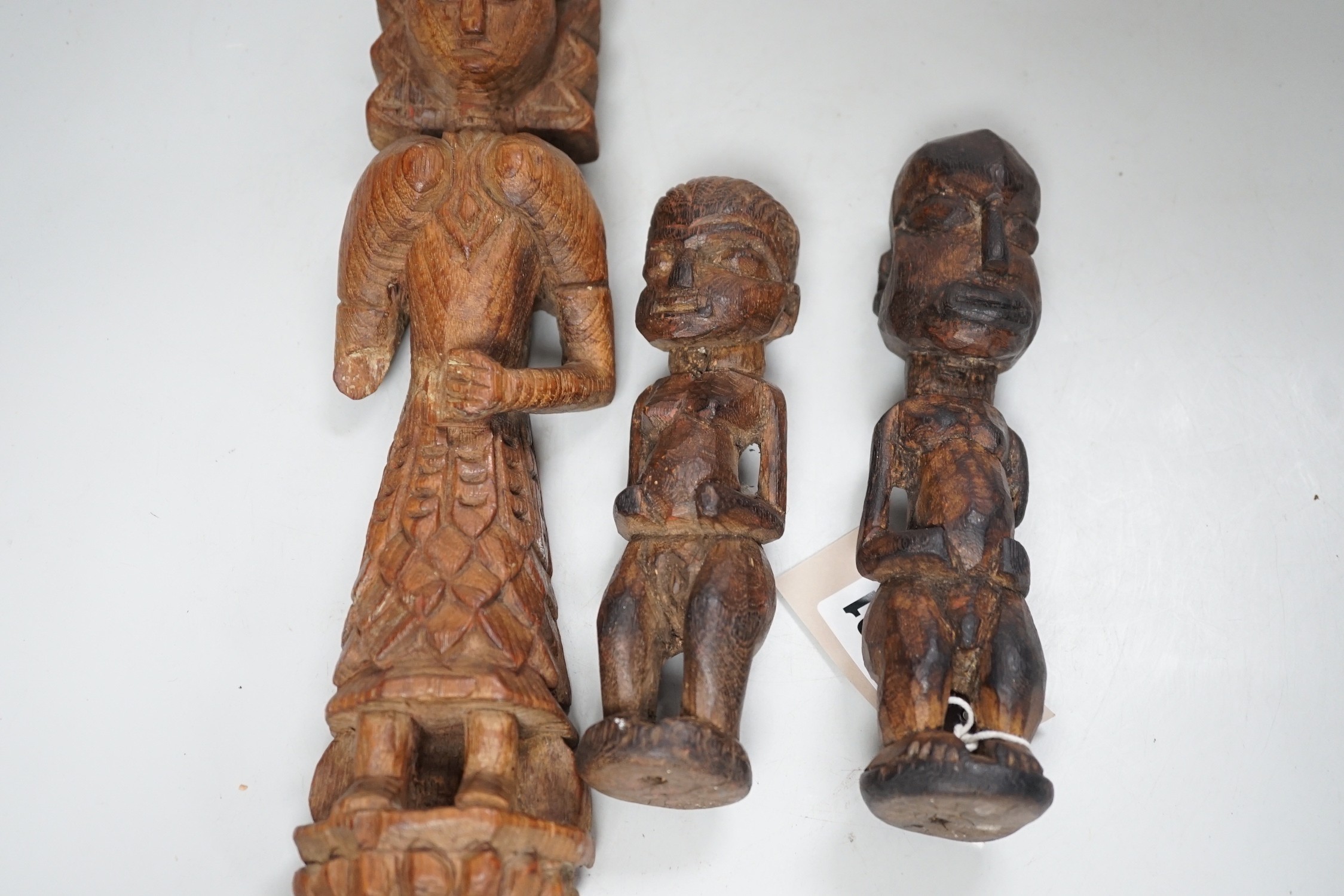 A carved teak terminal figure and two African tribal figures, largest 32cm long